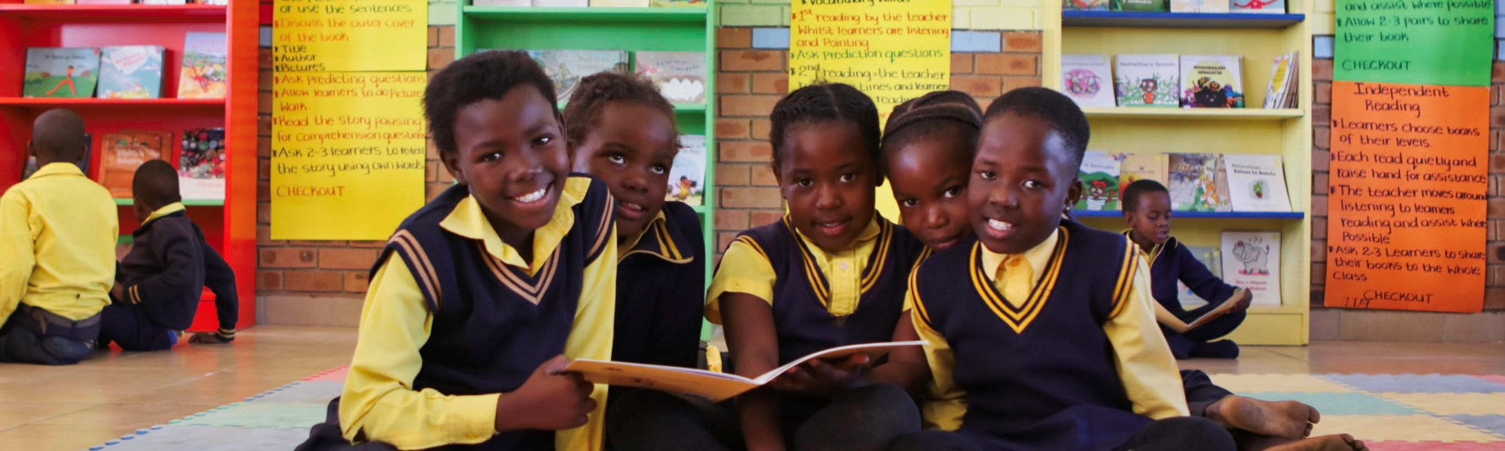 A group of primary school students in South Africa read together in a school library. 